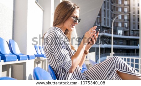 Portrait of beautiful woman in sunglasses using mobile phone on street