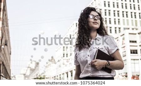 Young and pretty woman standing on the city background