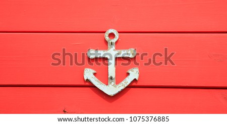 Anchor symbol on aged surface. Peeled sign, red blank board background, close up view.