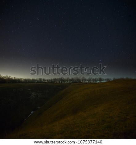 Bright stars in the night sky, forests and hills background. Landscape with a long exposure.
