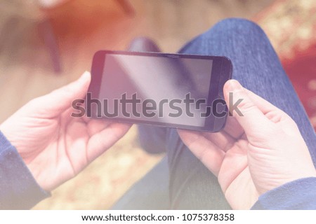 Closeup photo man hold and watching video mobile phone. Man sitting in vintage chair,holding smartphone and relaxing.Horizontal, film effect. Man entrepreneur is watching video on mobile phone.