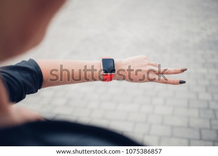 Female touching her smart watch with red strap
