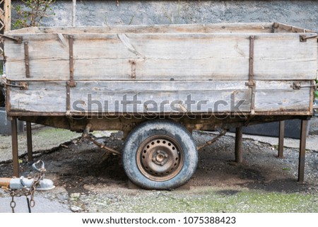 Small rustic wooden cart with old tires used for garden works. Vintage or obsolete transportation technology background.