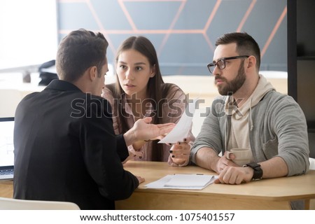 Angry millennial couple complaining having claims about bad contract terms disputing at meeting with lawyer, deceived dissatisfied customers demanding compensation, legal fight and fraud concept Royalty-Free Stock Photo #1075401557