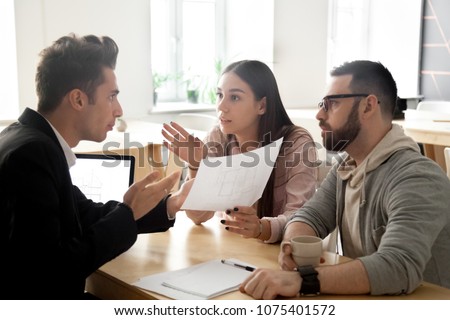 Angry deceived couple customers disputing about mortgage loan or real estate problem with realtor, lawyer or architect, clients having claim about house construction, bad contractor and fraud concept Royalty-Free Stock Photo #1075401572