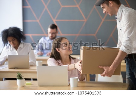 Office delivery service concept, millennial woman receiving box from courier holding package delivering to customer at work, smiling employee or happy worker accepting postal parcel at workplace