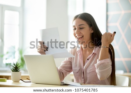 Happy young woman student or employee excited by reading good news in paper letter about new job, great deal, positive exam result, celebrating success or opportunity offered in written notification Royalty-Free Stock Photo #1075401785