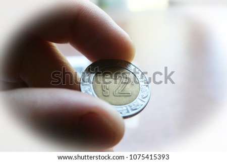 Mexican 2 Peso Coin In Hand With White Frame 