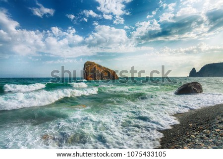 Sea waves crashing on the shore and flowing above seashore pebbles. Rocky seashore