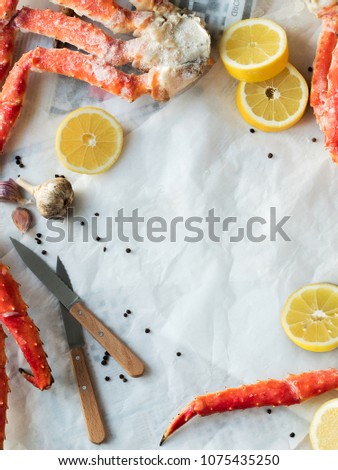Top view of fresh crab phalanges with lemon and spices on background of paper and newspapers with copy space.
