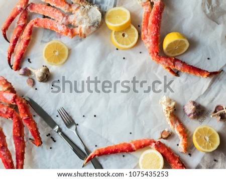 Top view of fresh crab phalanges with lemon and spices on rumpled paper with copy space.