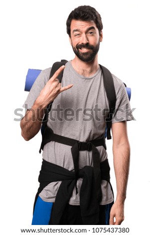 Handsome backpacker making rock gesture on white background