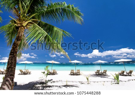 Sun umbrellas and chairs on tropical beach, Philippines, Boracay Royalty-Free Stock Photo #1075448288