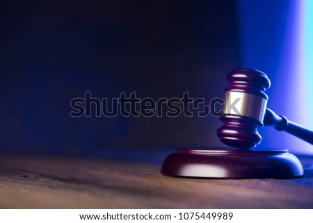 Law and justice concept. Gavel, wooden table, blue light.