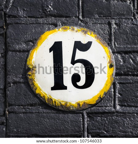 house number fifteen on a round weathered enameled plate