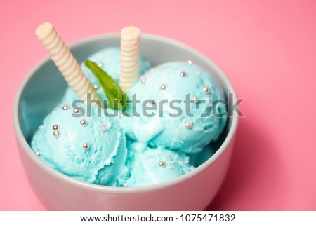 Pictachio ice cream with waffle sticks, several leaves of mint in bowl on pink background. copy space. gelato