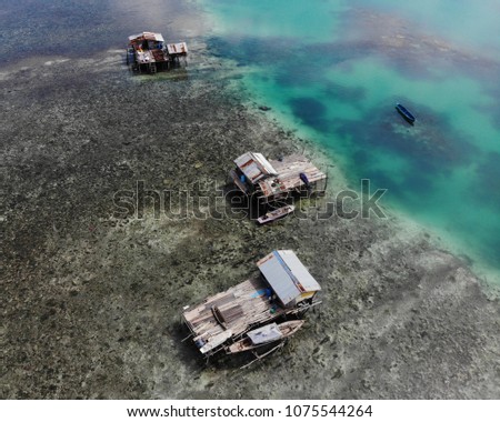 Aerial panoramic view of the Sea Gypsy homes known as Bajau Laut in Bintang Biru Island (Blue Star Island) in Semporna, Sabah, Malaysia. Beautiful blue lagoon and coral reef surrounded their homes.