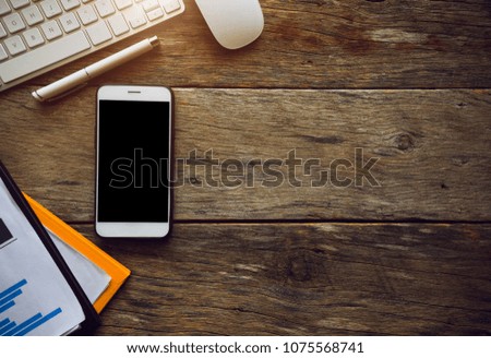 Office stuff with smartphone with blank screen and Laptop and notepad on the wooden table top view shot.