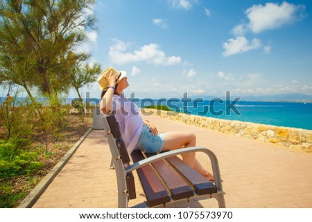 Resort vacation theme. Girl sitting on bench on seaside with amazing view at the sea.