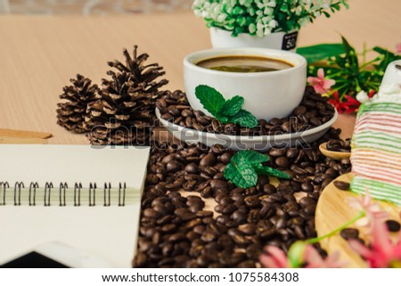 Cup of coffee on  coffee beans and leaf on the top left side wooden table with copy space.

