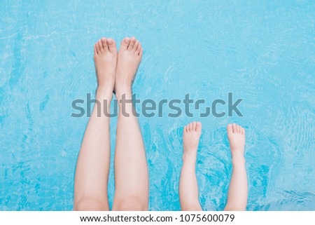 Child and adult legs underwater in the swimming pool