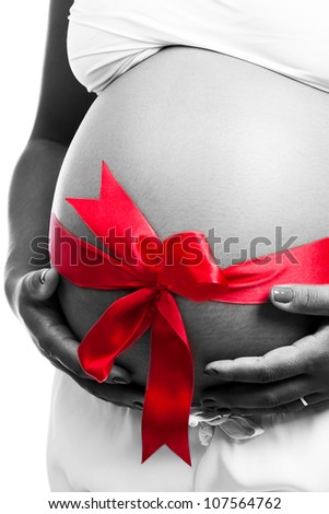 Pregnant belly and red gift ribbon.The belly in black and white and the ribbon is red.