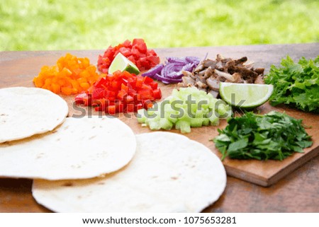 Tacos ingredients. Set of chopped fresh vegetables with beef, lime and tortillas on wooden board. 