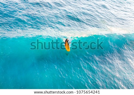 Surfer on a yellow surfboard on the crest of the wave, top view