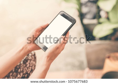 Close up hand woman holding and using phone in garden.