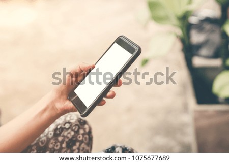 Close up hand woman holding and using phone in garden.