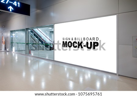 Mock up large advertisement signboard with clipping path near the sliding door entrance into airport terminal hall, empty white space for advertising or information to public transportation.