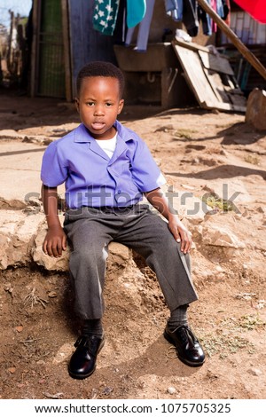 Little black boy sitting in his yard in the township.