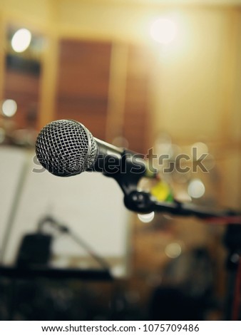 Enjoy music concept microphone on blurred background of guitar transmitter wireless on note stand in live recording studio with bokeh defocused lights. (space for text, article layout design)