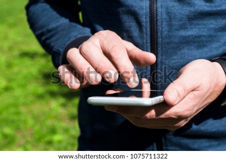 A man uses a smartphone outdoor. Man's hands push on the phone. Modern online lifestyle 