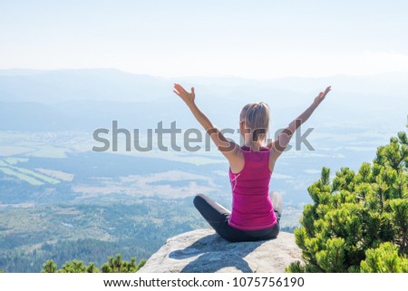 young woman meditate on top of the mountain