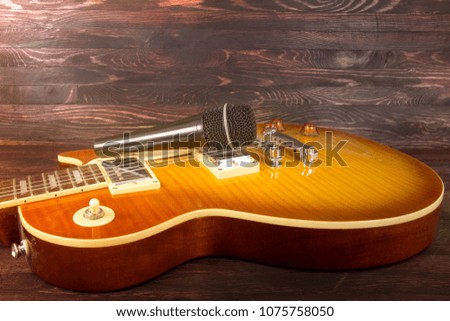electric guitar and microphone on wooden background