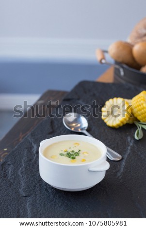 Corn soup in bowl with fresh corn cob on the side.