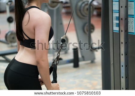 A wonmen is pulling  rope that was tided with fitness machine