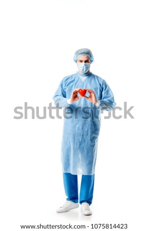 Surgeon wearing blue uniform and holding toy heart isolated on white