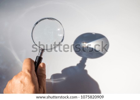 Left hand holding old magnifying glass on white background, Light and Shadow