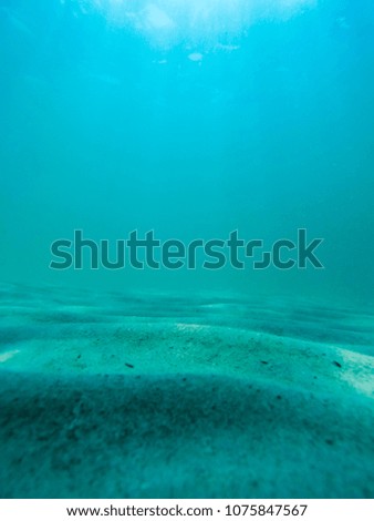 Underwater scene with sunlight through water surface to bottom of sand side