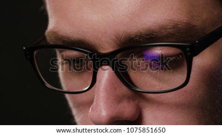 A close-up of a young man's face against a black background. Macro shot