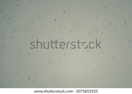 Rain drops on window glasses surface on the dark cloudy sky background