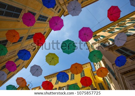 Multicolored umbrellas in the sky above the streets in the center of Genoa, Italy.