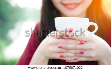 Closeup image of Asian woman smelling and drinking hot coffee with feeling good in cafe,Top view image of Asian woman holding and smelling with hot milk and coffee feeling good in cafe,