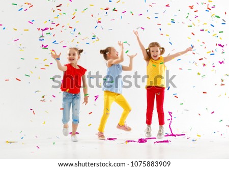 happy children on holidays have fun and  jumping in multicolored confetti on white background
