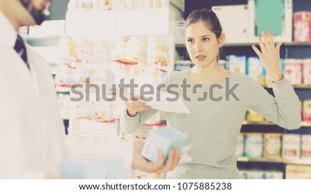 Portrait of unhappy woman client who is dissatisfied of recommended medicines in pharmacy. Royalty-Free Stock Photo #1075885238