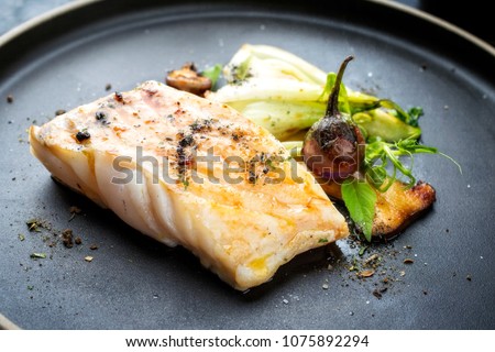 Modern Thai fried cod fish filet with bok choi and mushrooms as close up on a plate 