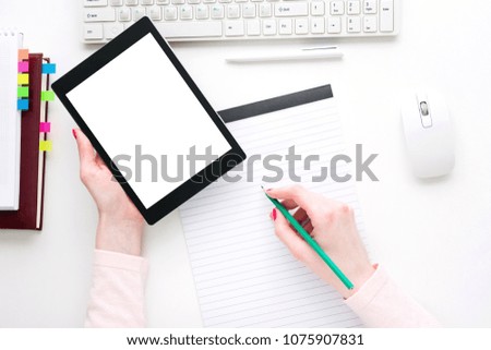 white Desk, women's hands, red manicure, girl writing in Notepad, holding a tablet computer, keyboard, red manicure, top view, white background with copy space, for advertising