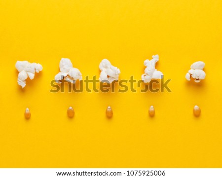Corn grains and popcorn in a row on yellow background. Concept of evolution and growth. Horizontal image. Top view. Royalty-Free Stock Photo #1075925006